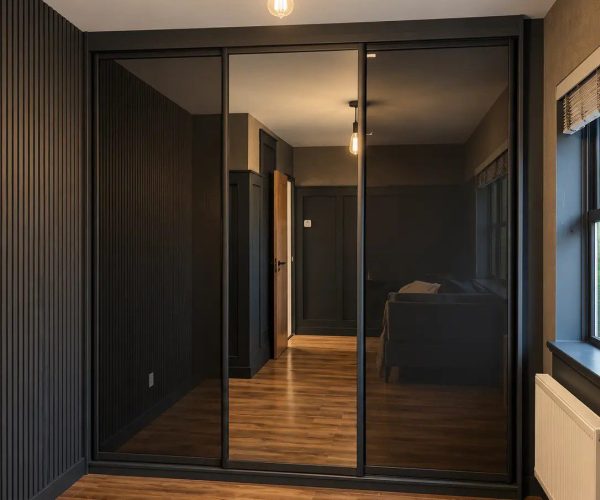 Luxury dark coloured fitted wardrobes with mirrored sliding doors and a contemporary bedroom design.